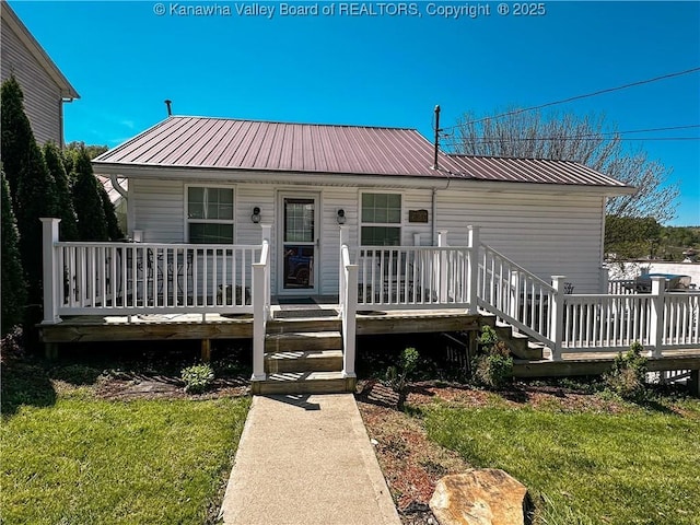 view of front facade with a front yard, covered porch, and metal roof