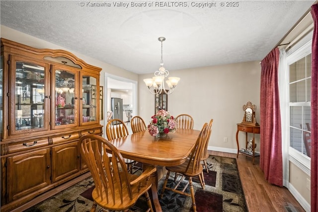 dining area with a chandelier, dark wood finished floors, a textured ceiling, and baseboards