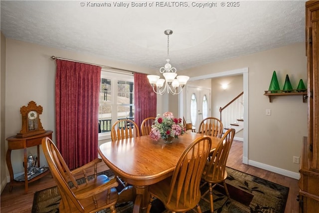 dining space with a textured ceiling, baseboards, and wood finished floors