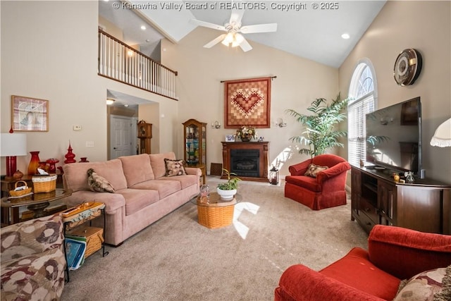 living room featuring carpet floors, a fireplace, high vaulted ceiling, and ceiling fan