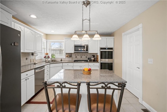 kitchen featuring white cabinetry, appliances with stainless steel finishes, backsplash, and a breakfast bar area