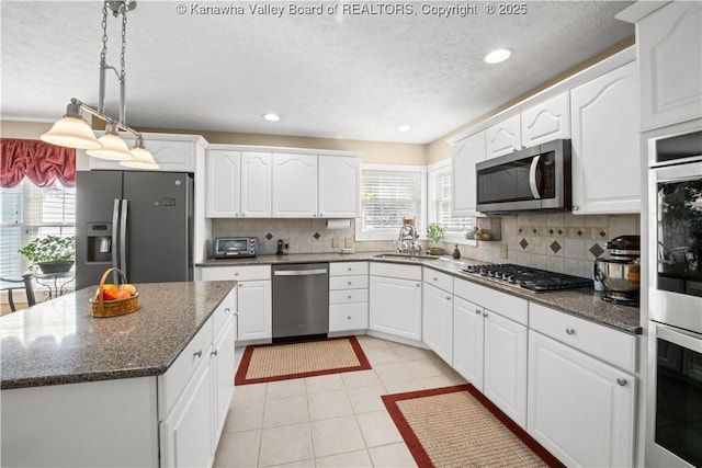 kitchen with stainless steel appliances, plenty of natural light, and white cabinetry