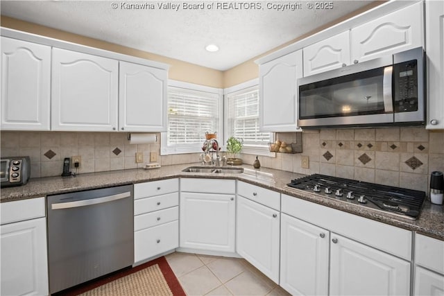 kitchen with stainless steel appliances, backsplash, light tile patterned flooring, and a sink