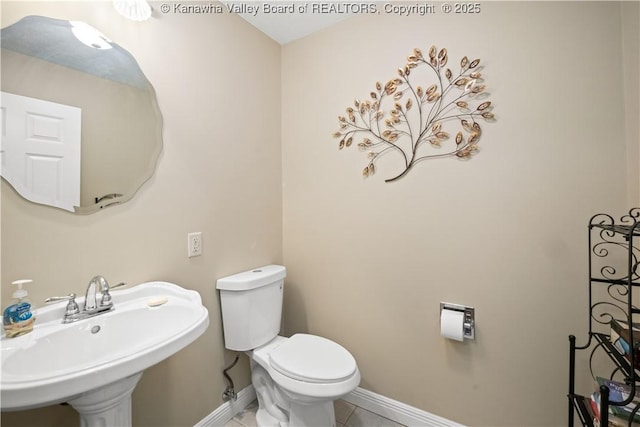 bathroom featuring baseboards, a sink, toilet, and tile patterned floors