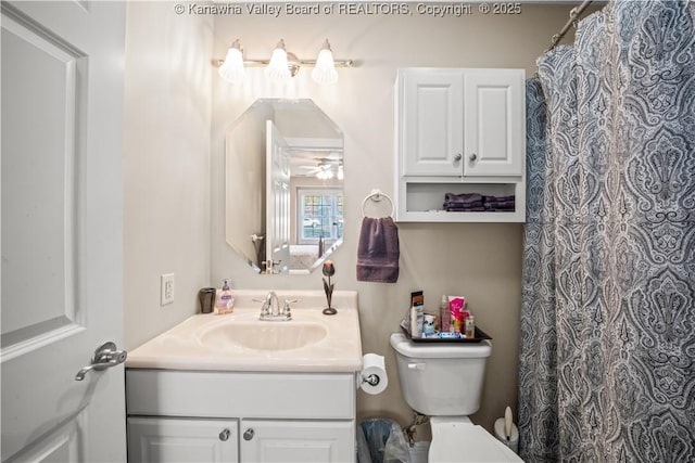 bathroom with toilet, curtained shower, ceiling fan, and vanity