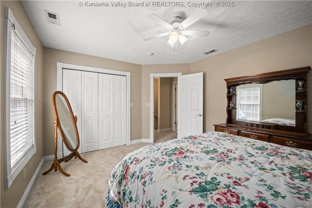 bedroom featuring a textured ceiling, visible vents, a closet, and light colored carpet