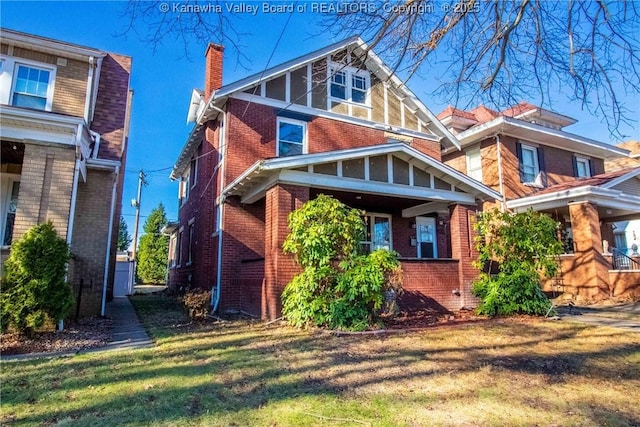 view of front of house featuring a front yard, a chimney, and brick siding