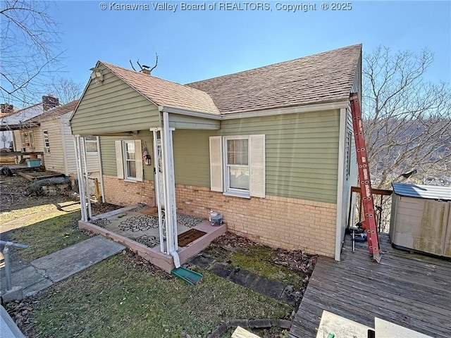 view of side of property featuring a shingled roof and brick siding