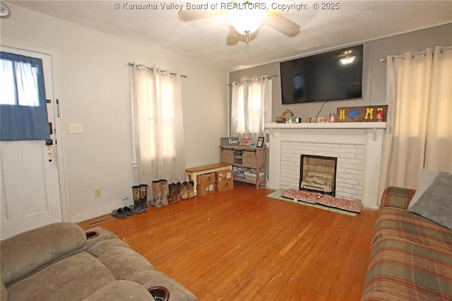 living room with a fireplace, wood finished floors, and a ceiling fan