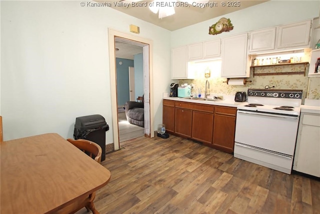 kitchen with tasteful backsplash, dark wood finished floors, light countertops, white electric range, and a sink