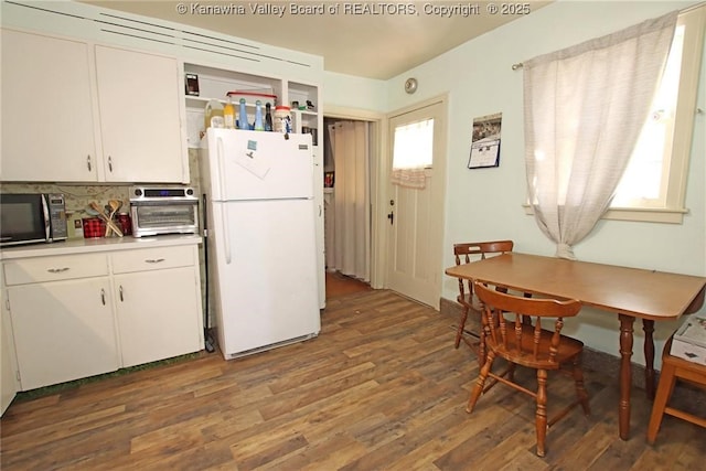 kitchen with a wealth of natural light, freestanding refrigerator, black microwave, and wood finished floors