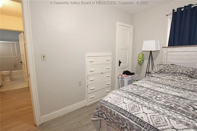 bedroom with light wood-type flooring, ensuite bath, and baseboards