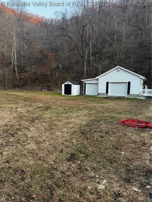 view of yard with a garage, an outbuilding, and fence