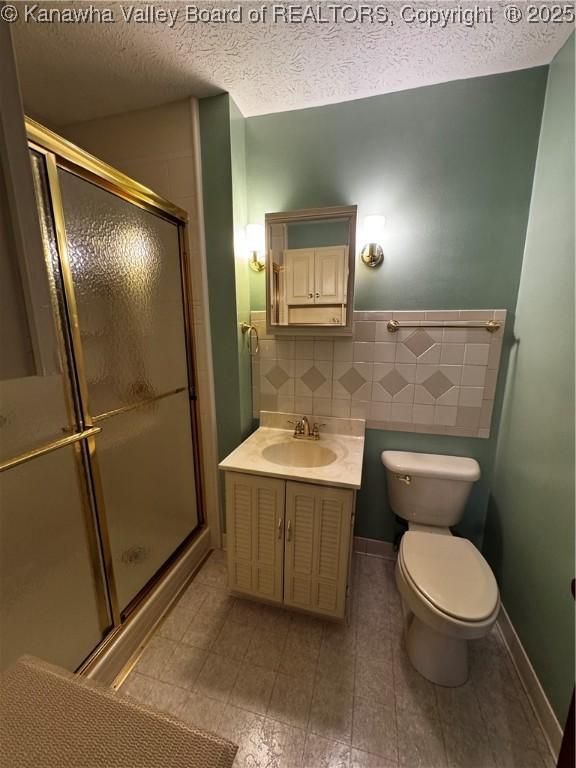 bathroom featuring a stall shower, toilet, a textured ceiling, vanity, and backsplash