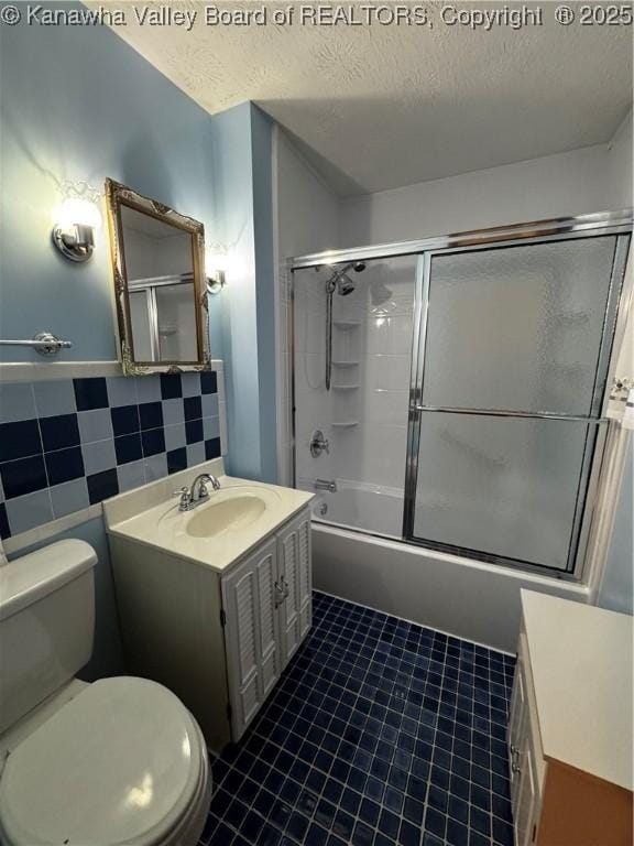 full bath featuring tile walls, a textured ceiling, toilet, and vanity