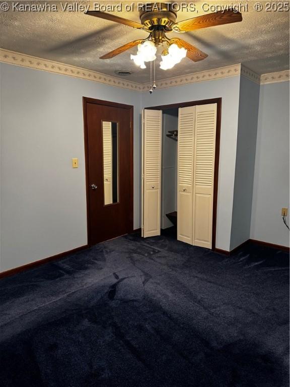 unfurnished bedroom featuring a textured ceiling, a closet, dark carpet, and baseboards