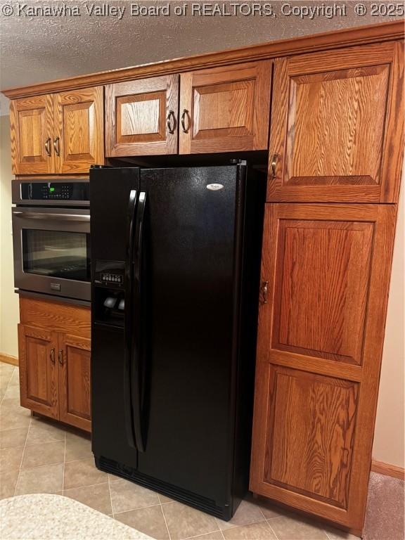 kitchen featuring wall oven, brown cabinets, and black fridge with ice dispenser