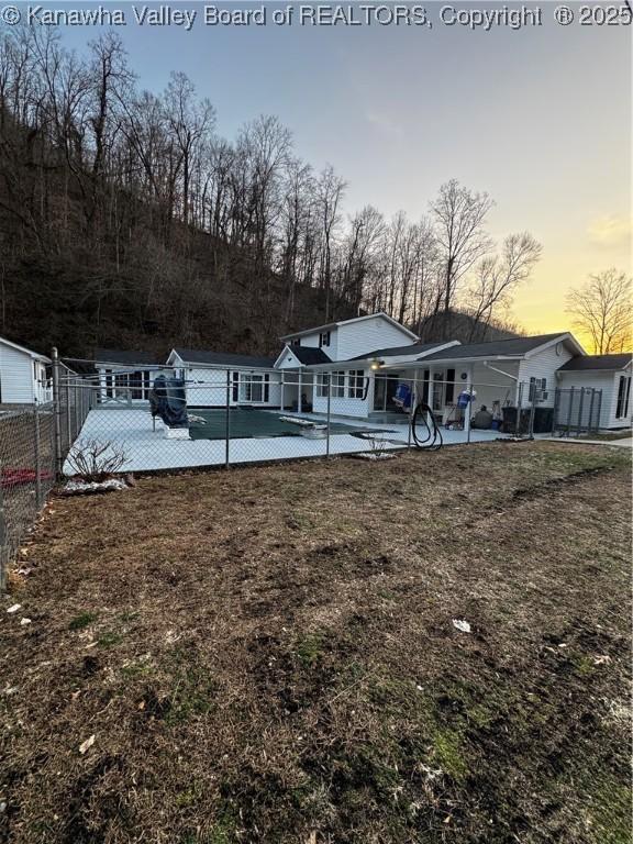 rear view of house featuring fence, a patio, and a lawn