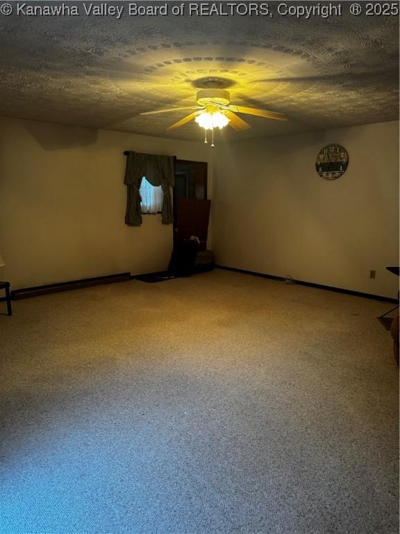 unfurnished room with a textured ceiling, ceiling fan, and baseboards