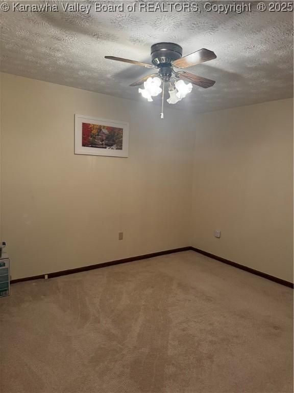 carpeted empty room with ceiling fan, a textured ceiling, and baseboards