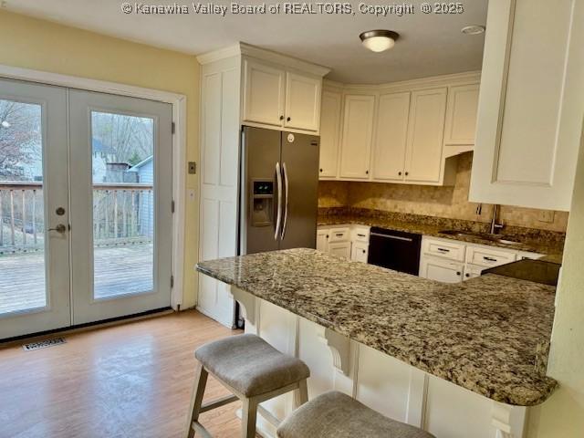 kitchen featuring tasteful backsplash, black dishwasher, dark stone counters, french doors, and a sink