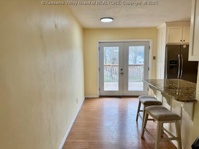 doorway with baseboards, wood finished floors, and french doors