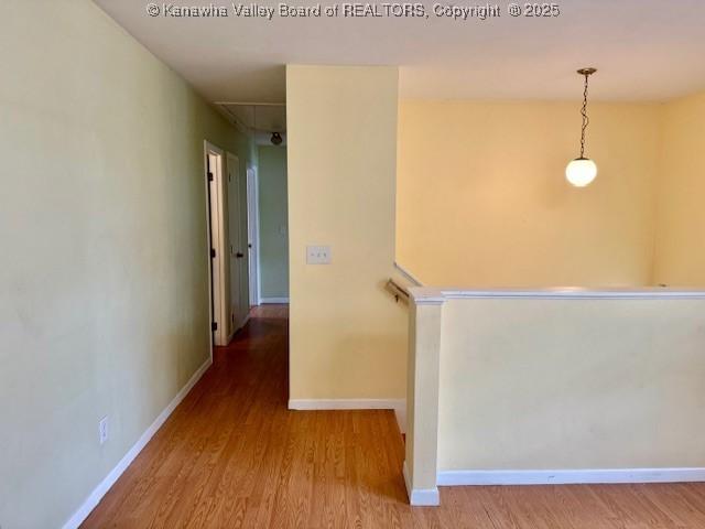 hallway with wood finished floors, attic access, and baseboards