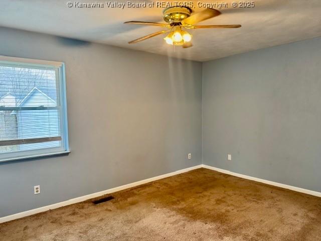 carpeted spare room with visible vents, ceiling fan, and baseboards