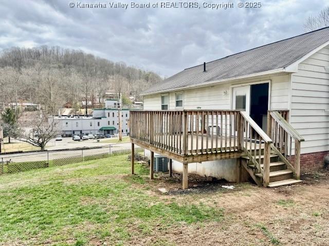 exterior space featuring a lawn, cooling unit, fence, and a wooden deck