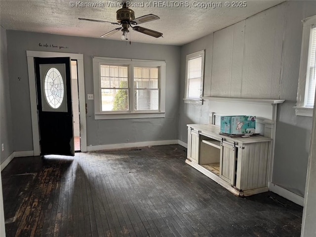 foyer entrance featuring a ceiling fan, a textured ceiling, baseboards, and dark wood-style flooring