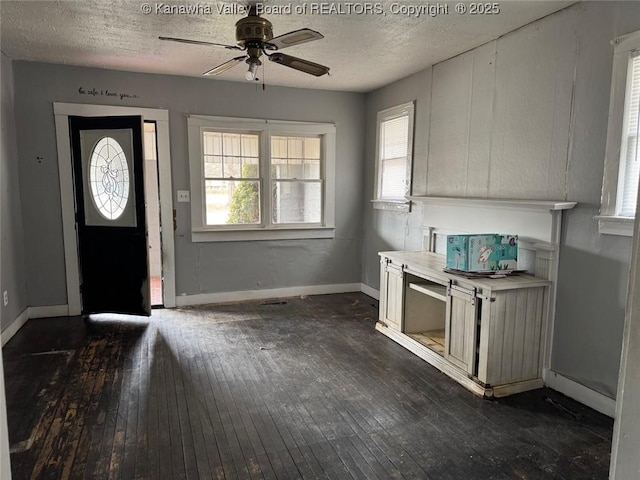 entrance foyer with a ceiling fan, a textured ceiling, baseboards, and dark wood-style flooring