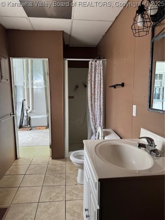 bathroom with a stall shower, toilet, tile patterned flooring, vanity, and a paneled ceiling