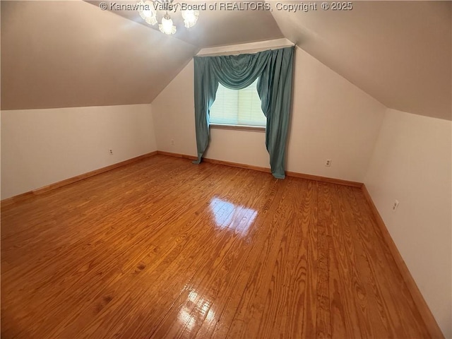 additional living space with vaulted ceiling, wood finished floors, and baseboards