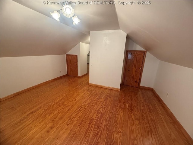 additional living space with vaulted ceiling, baseboards, and wood finished floors