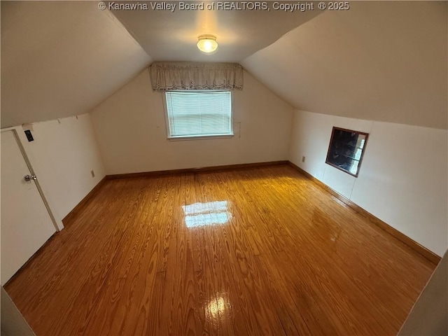 bonus room with vaulted ceiling, light wood-type flooring, and baseboards