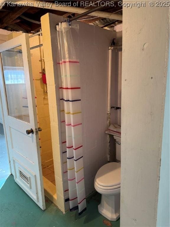 full bathroom with toilet, a shower stall, and concrete flooring