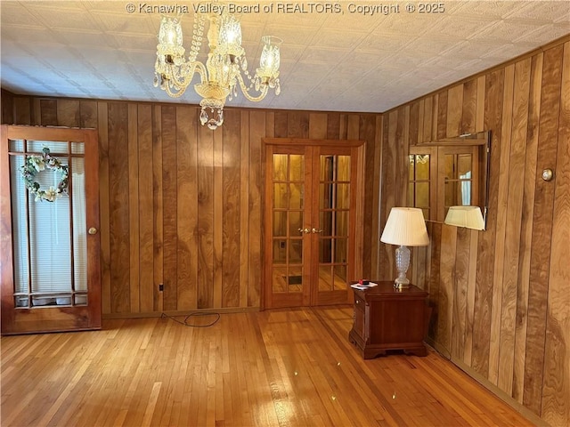 interior space with wood walls, wood-type flooring, and a notable chandelier