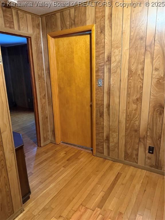 corridor featuring light wood-style floors and wood walls