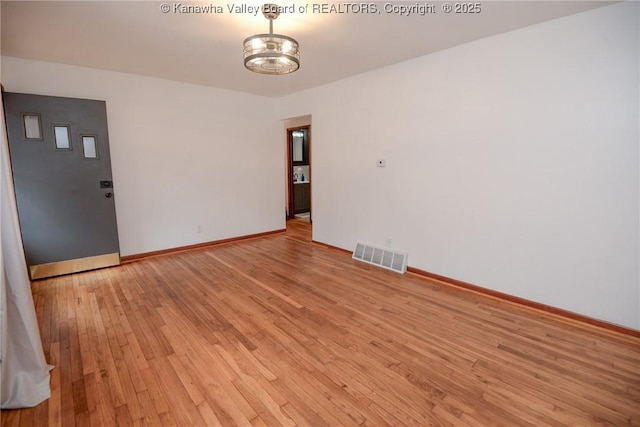 spare room with light wood-style floors, baseboards, and visible vents