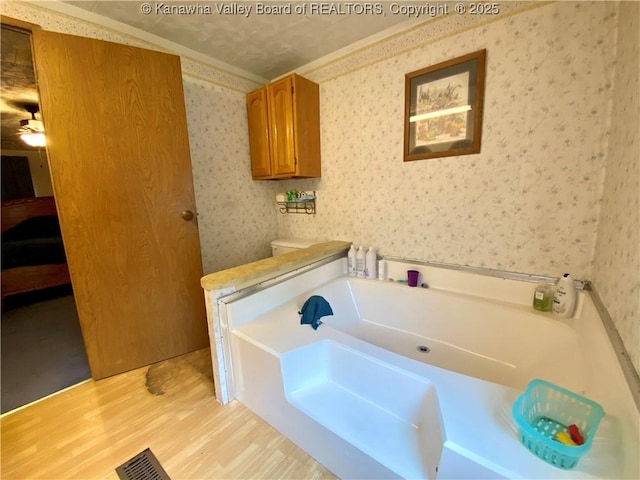 full bath with a garden tub, visible vents, ensuite bath, wood finished floors, and wallpapered walls