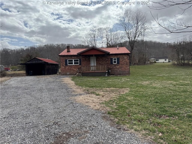 chalet / cabin featuring a chimney, metal roof, gravel driveway, a front lawn, and brick siding