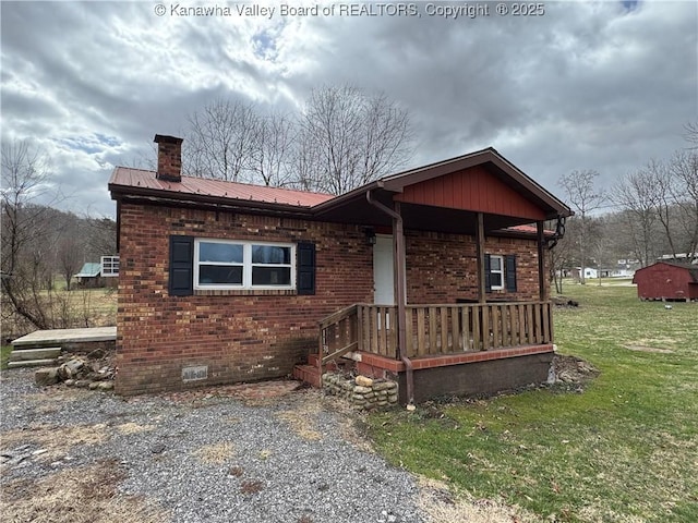 chalet / cabin with metal roof, brick siding, crawl space, a chimney, and a front yard