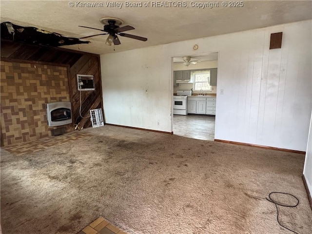 unfurnished living room with wooden walls, a ceiling fan, heating unit, a textured ceiling, and carpet floors