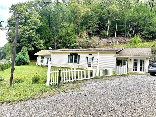 ranch-style house with driveway, french doors, a fenced front yard, and a front yard