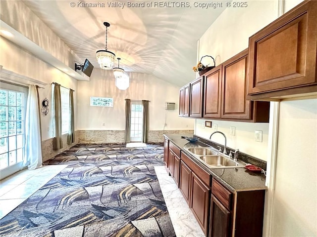 kitchen with hanging light fixtures, dark countertops, a sink, and a wealth of natural light