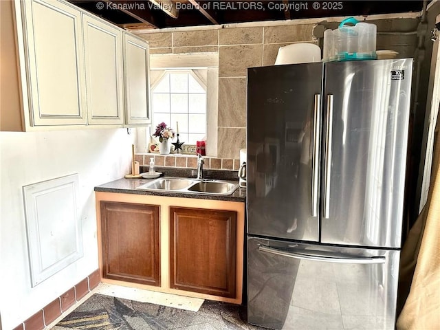 kitchen with freestanding refrigerator, brown cabinets, a sink, and dark countertops