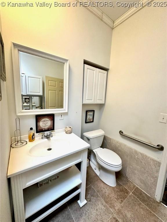 half bath featuring toilet, ornamental molding, and vanity
