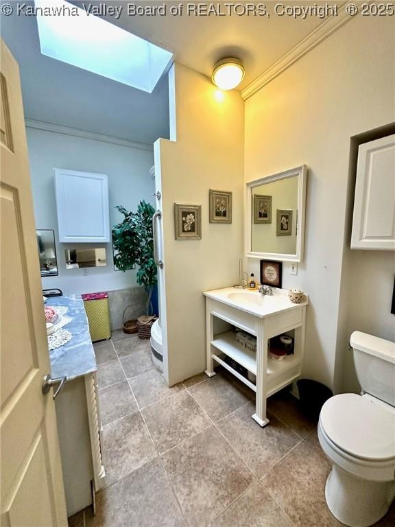 bathroom featuring a skylight, crown molding, vanity, and toilet