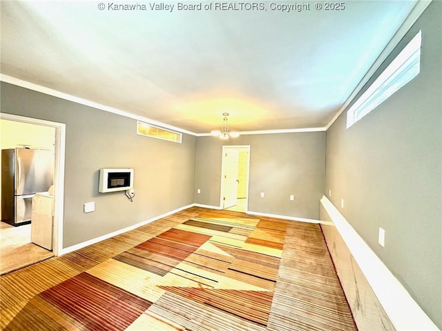 interior space with a chandelier, ornamental molding, and baseboards