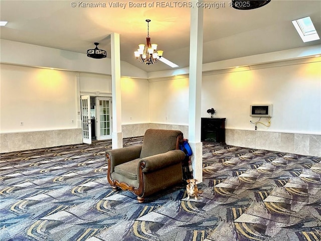 interior space with lofted ceiling with skylight, carpet, and an inviting chandelier